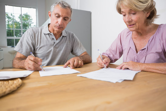 Couple signing documents together in the kitchen