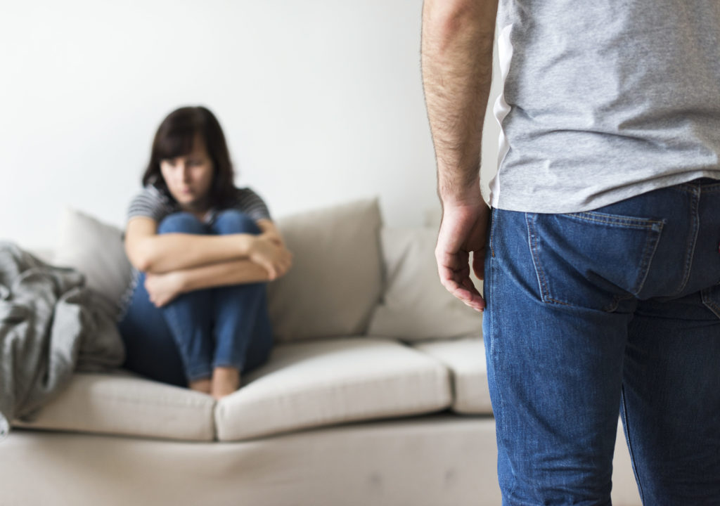 A woman sitting on a sofa with a man in the foreground