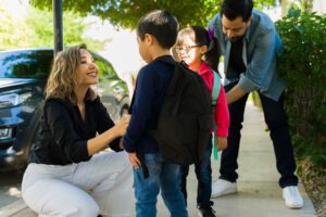 Happy beautiful parents and family dropping off their kids with backpacks at school while smiling